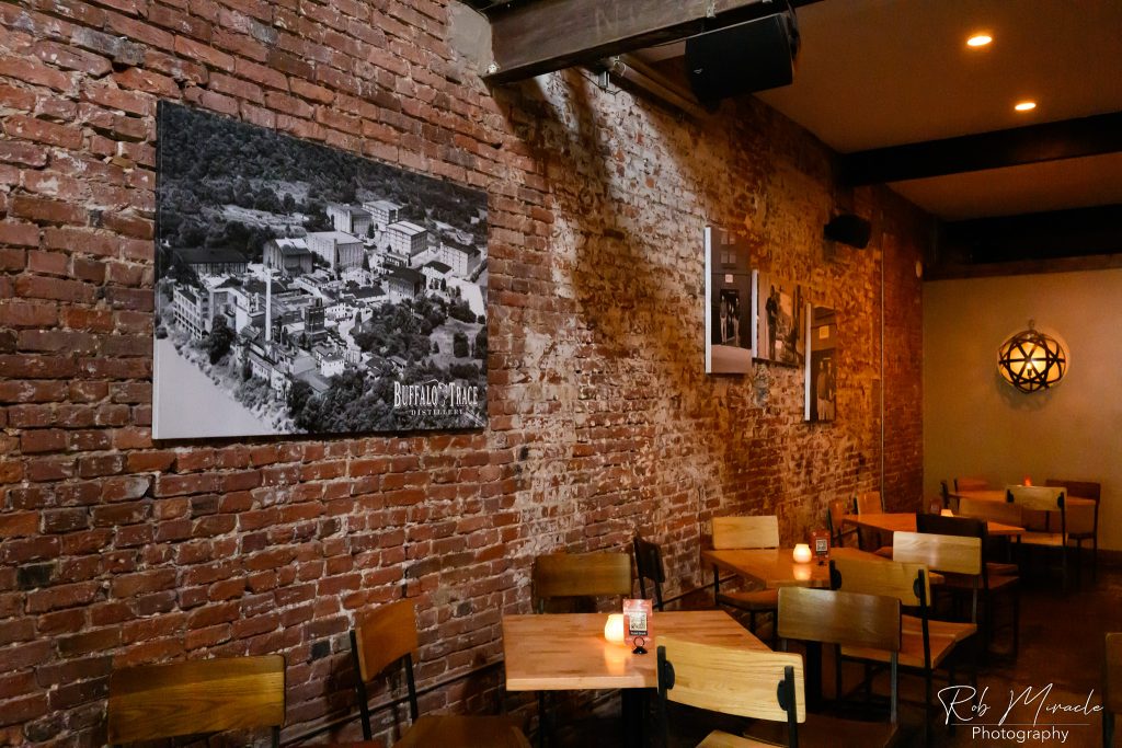 View of Merle's Whiskey Kitchen's dining area with old photos of various bourbon and whiskey themed photos on the wall.